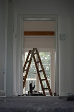 Modernisierung Leiter steht im Zimmer Leiter bei Malerarbeiten im Haus. Blickwinkel aus anderem Zimmer, bei dem die Zimmertüre ausgehängt ist.
